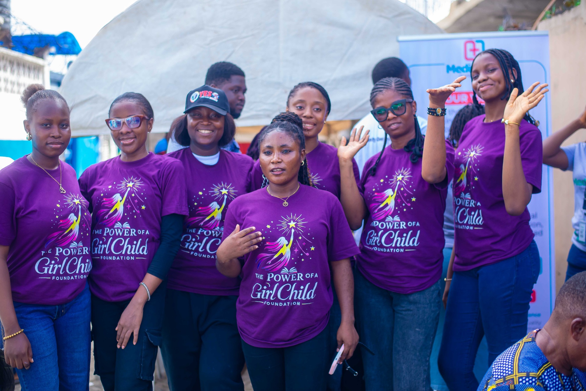 Power of a Girl Child volunteers waving